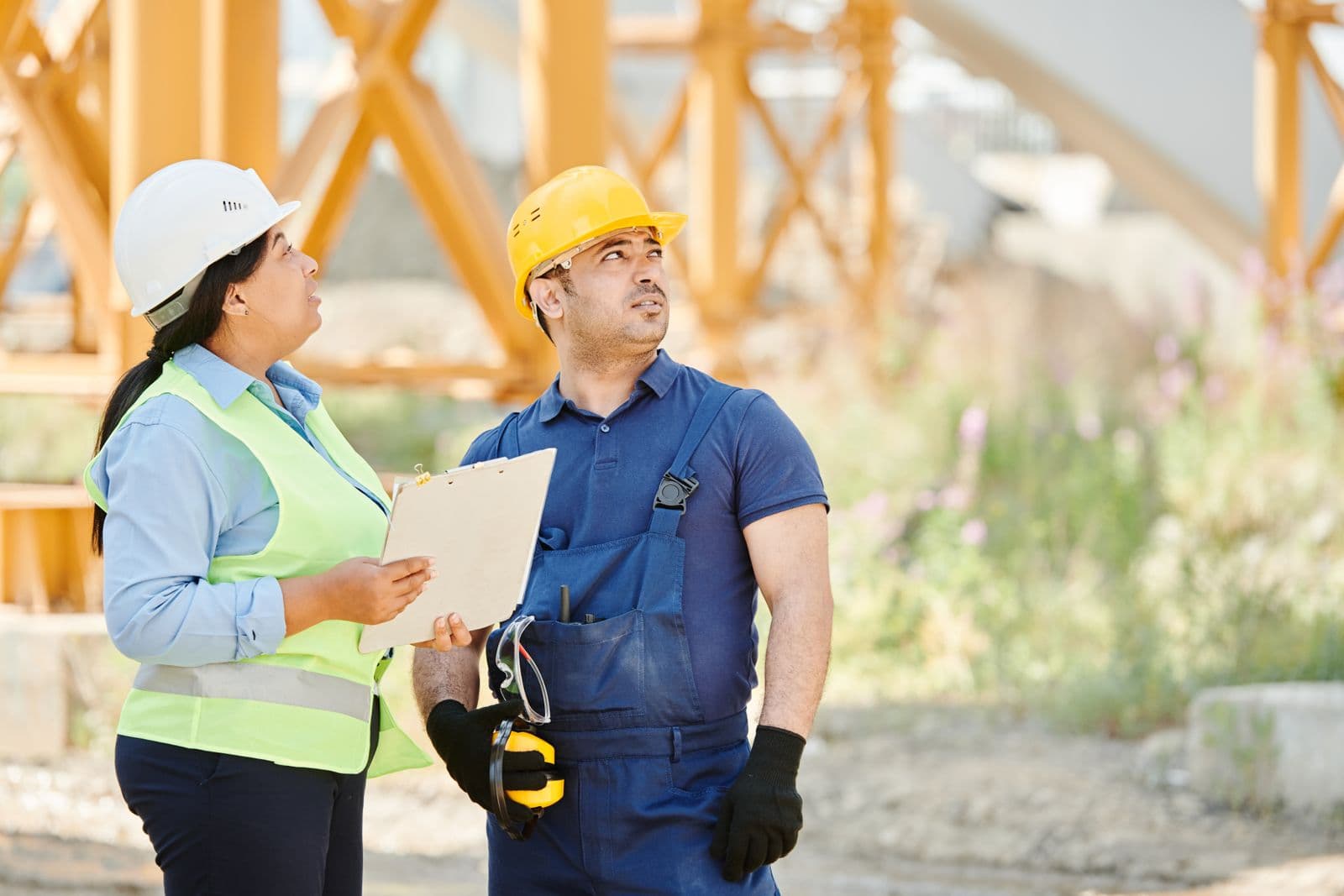 Mentor and technician in hard hats reviewing a checklist together on a jobsite.
