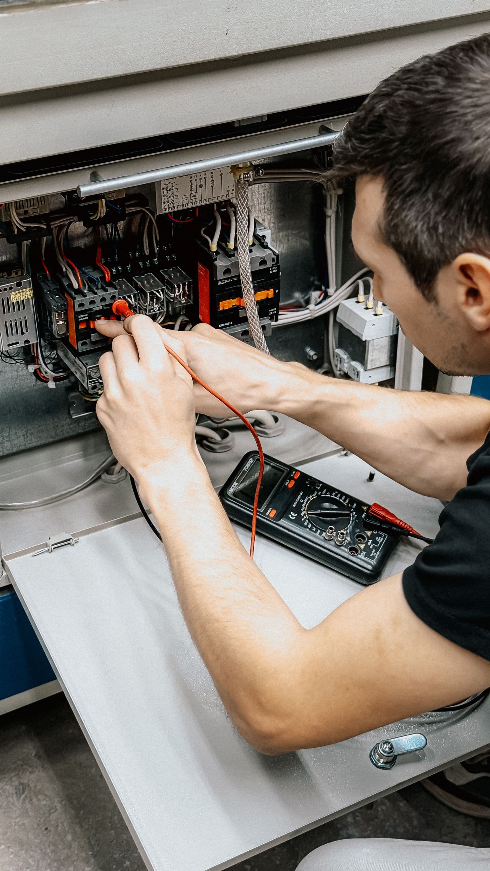 A service technician testing a control panel with a multimeter