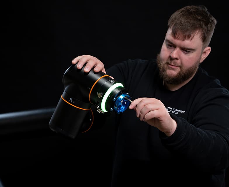 A technician working beside a collaborative robot arm during setup