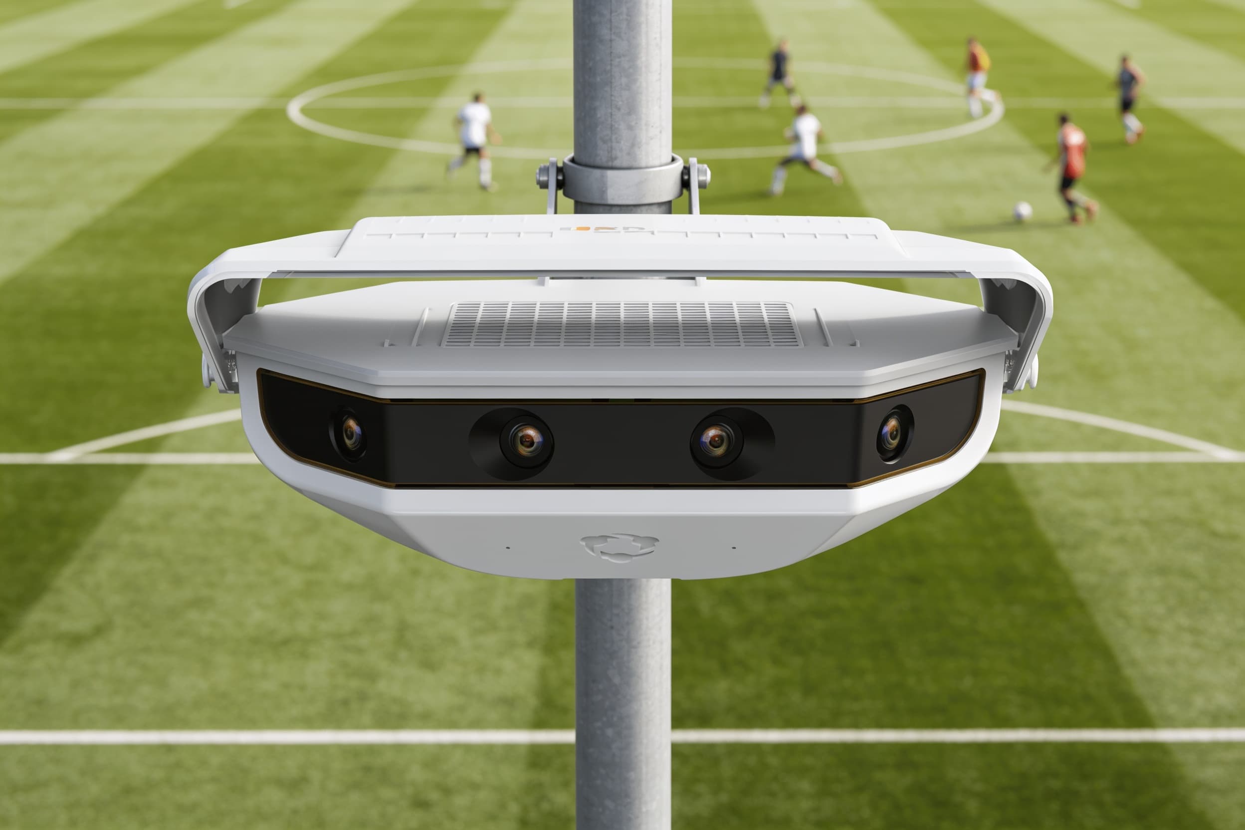 A pole-mounted camera unit above an open turf field