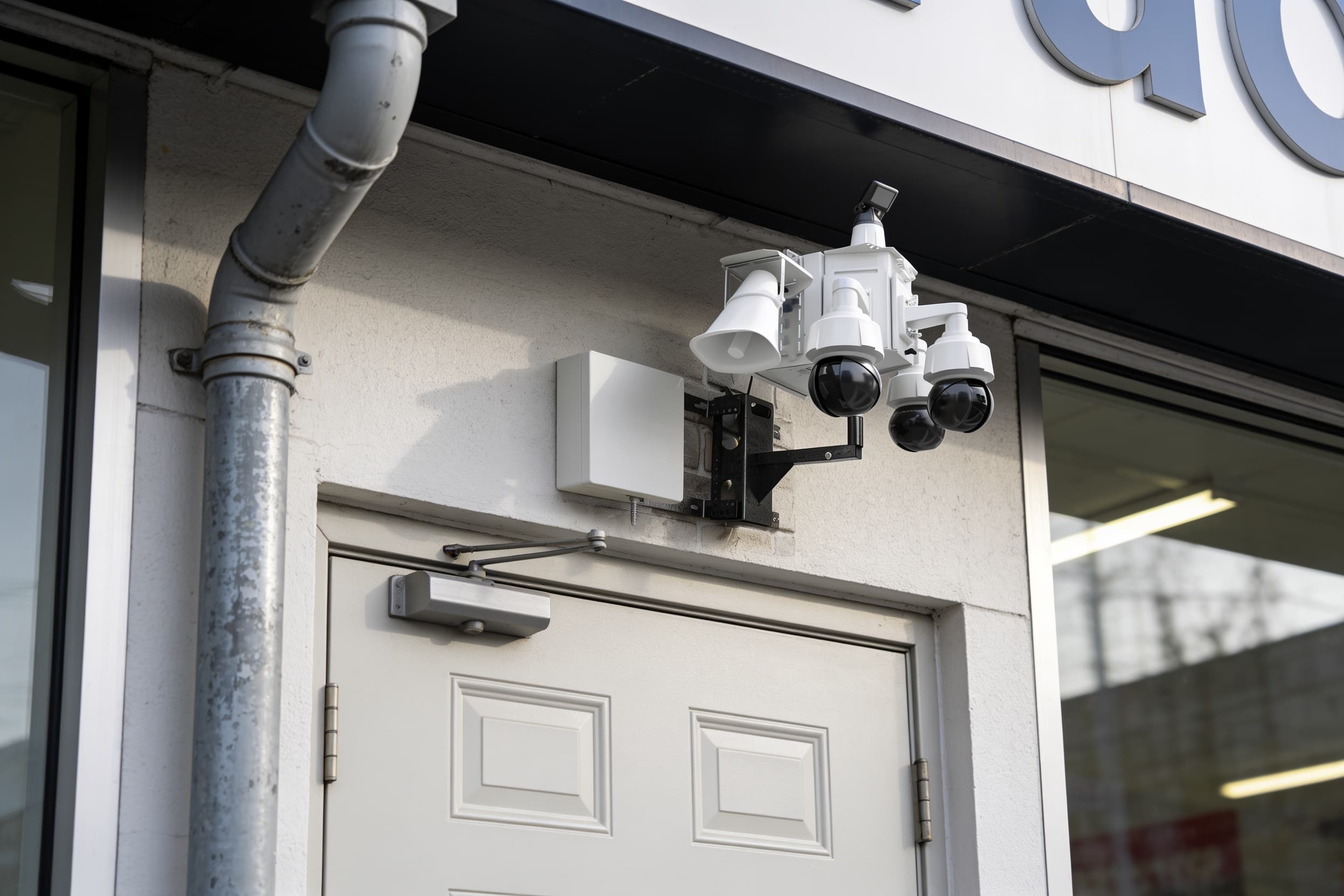 Building-mounted security camera above a retail service door