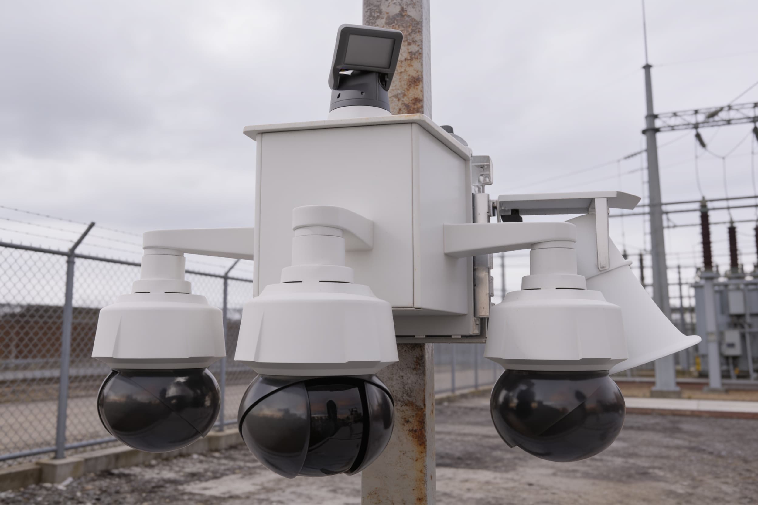A pole-mounted camera unit at a substation perimeter