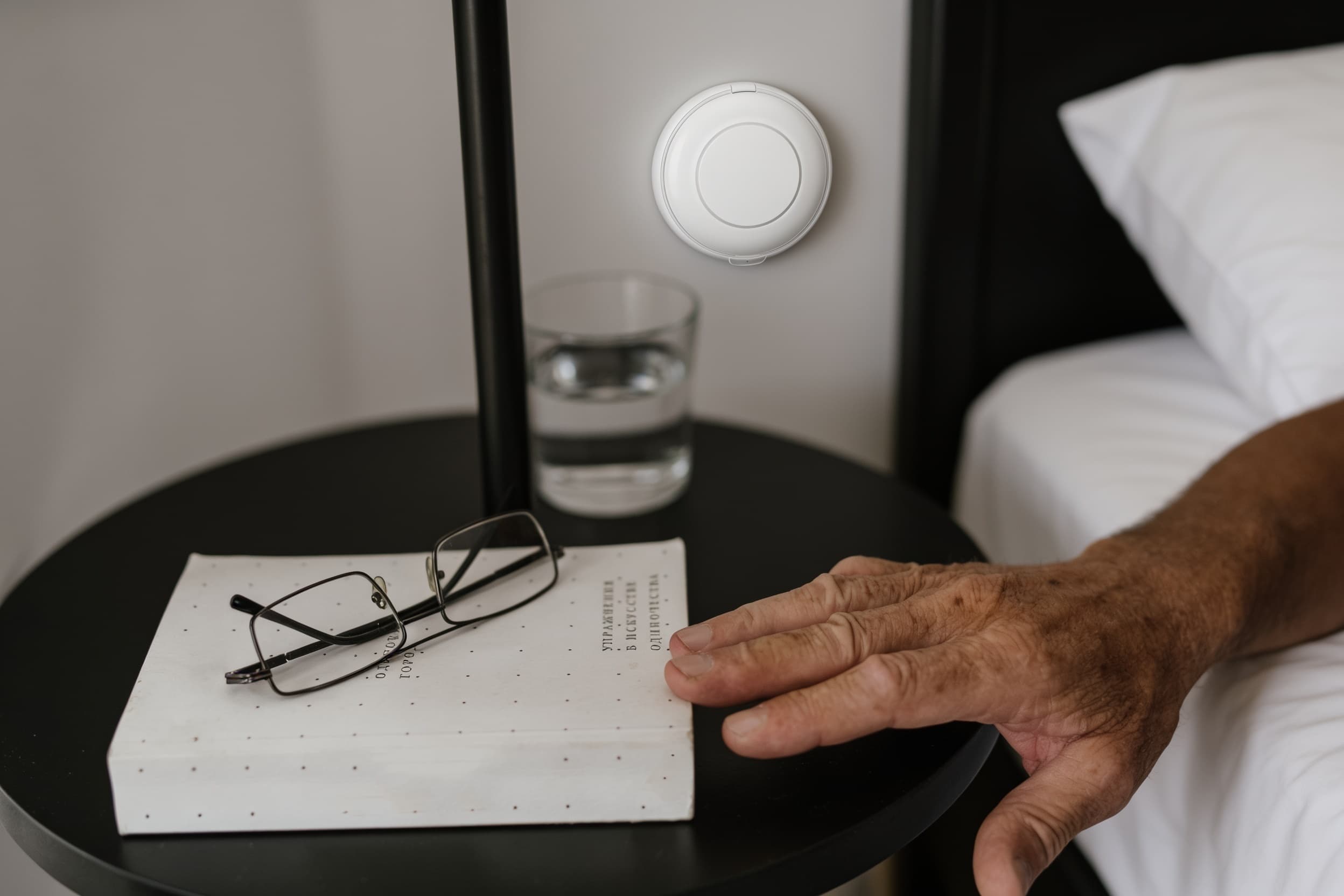 A wall-mounted alert button beside the bed in a senior living bedroom